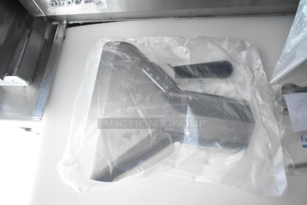 Plastic-wrapped metal component, possibly an appliance part, on a white surface in a mobile kitchen setting.