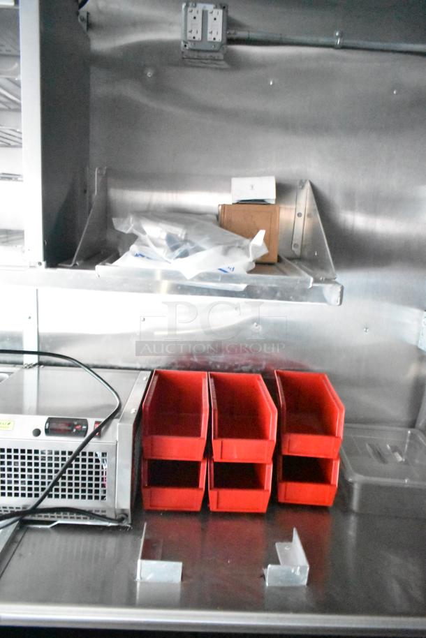 Interior of Rock Solid Cargo fast food trailer with red storage bins, stainless steel surfaces, and electrical outlets above.