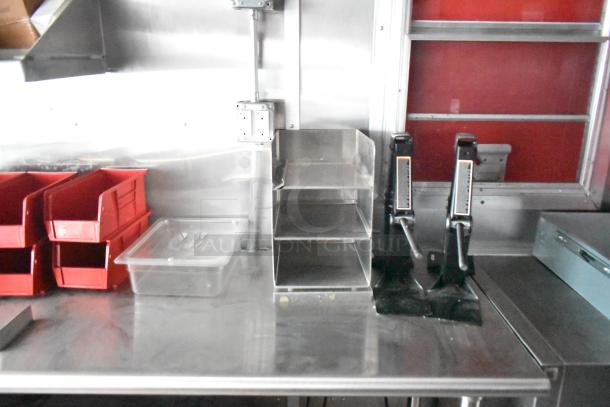 Rock Solid Cargo fast food trailer interior with stainless steel countertop, red storage bins, and shelving, ideal for mobile kitchen use.
