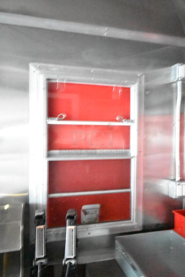 Rock Solid Cargo fast food trailer interior, featuring stainless steel fixtures, shelving, and a service window.