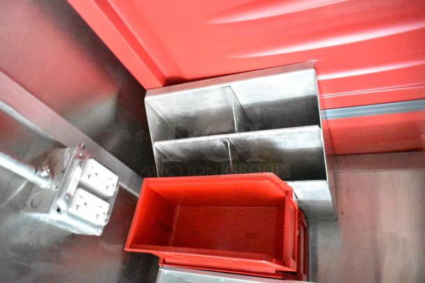 Inside view of Rock Solid Cargo fast food trailer showing storage compartments and power outlets. Red and metallic surfaces.