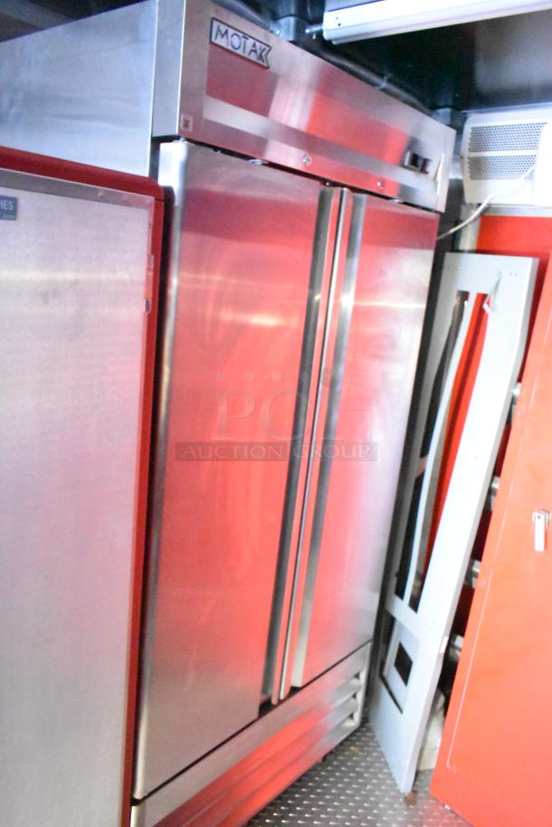 Commercial-grade stainless steel double-door Motak refrigerator inside Rock Solid Cargo fast food trailer, new condition.