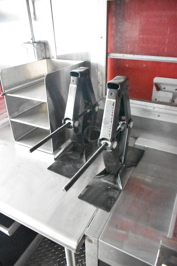 Rock Solid Cargo fast-food trailer interior with stainless steel counters and equipment, including black metal jacks.