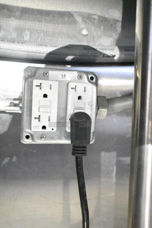 Electrical outlet inside Rock Solid Cargo fast food trailer, showing dual sockets and labeled "14," part of kitchen setup.