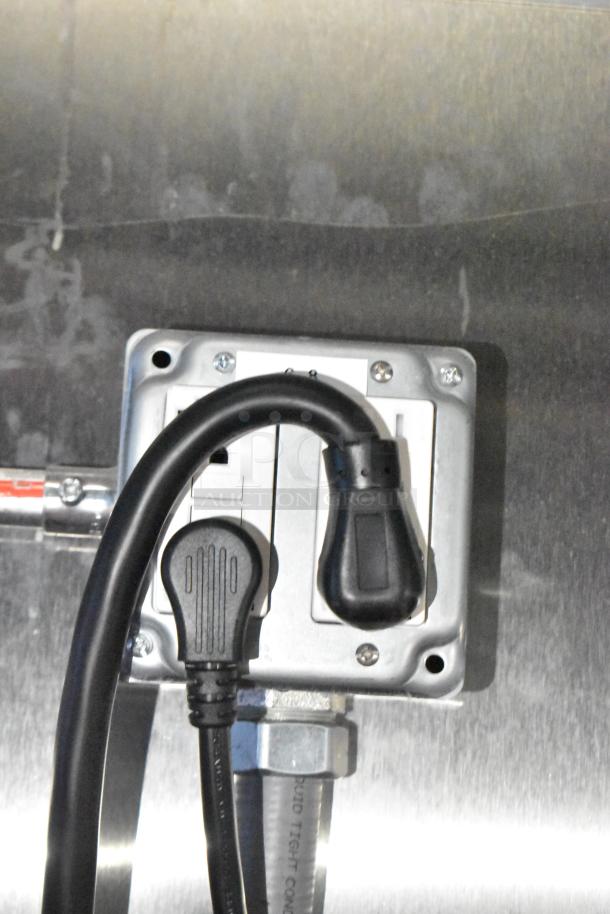Power outlet with black plug connected, part of the Rock Solid Cargo fast food trailer's electrical system.