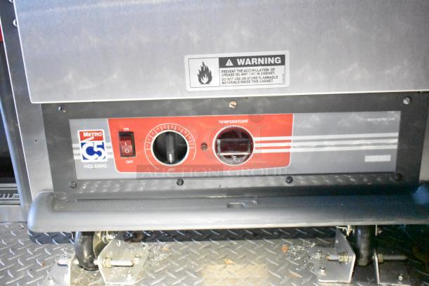 "Metro C5 holding cabinet with temperature control dial and warning label in mobile kitchen trailer."