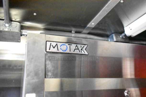 Interior of Rock Solid Cargo mobile kitchen with visible stainless steel surface and Motak equipment label.