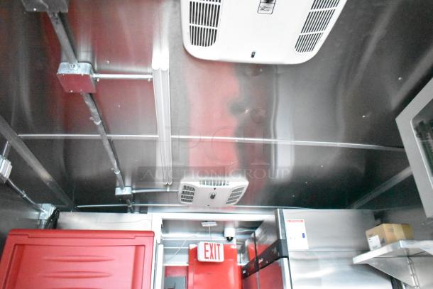 Interior ceiling of Rock Solid Cargo mobile kitchen trailer, showing lighting, ventilation, and red door panel.