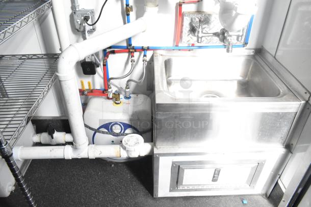 Southern Dimensions 24' cold food trailer interior with stainless steel sink, piping, and wire shelving. Fully equipped.