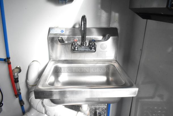 Stainless steel commercial sink in a Southern Dimensions food trailer, featuring hot and cold levers, NSF certified.