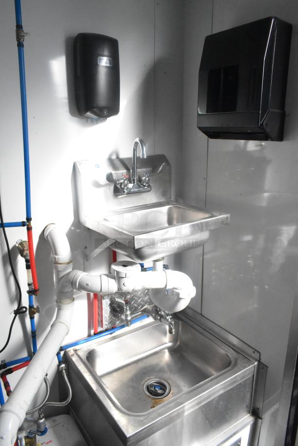 Stainless steel sink setup with faucet, plumbing, and dispensers in Southern Dimensions 24' retail trailer.