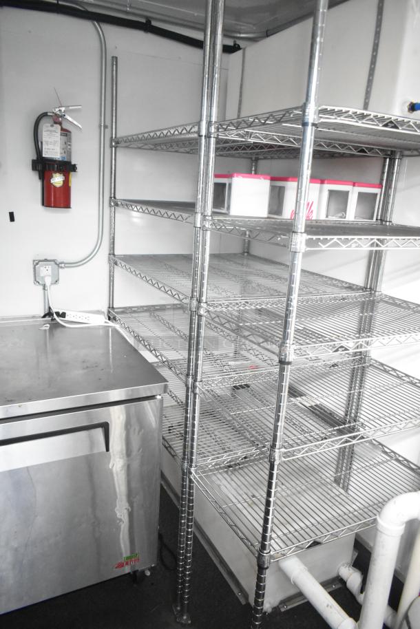 Southern Dimensions 24' unbranded cold food trailer interior with wire shelving, True cooler, and fire extinguisher.