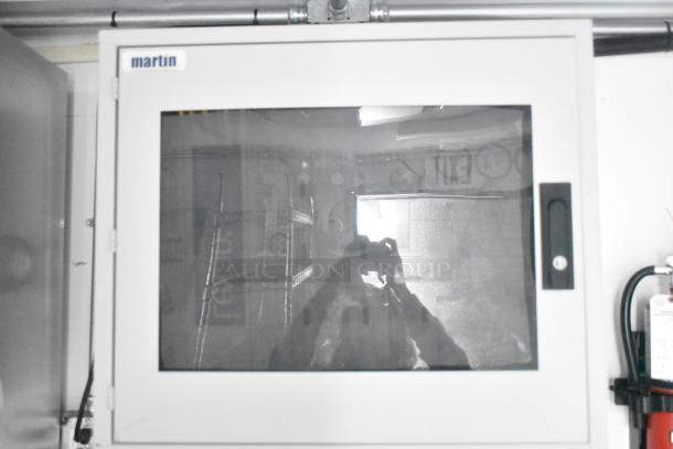 White control panel with a glass door, labeled "martin," mounted in a food and beverage trailer.