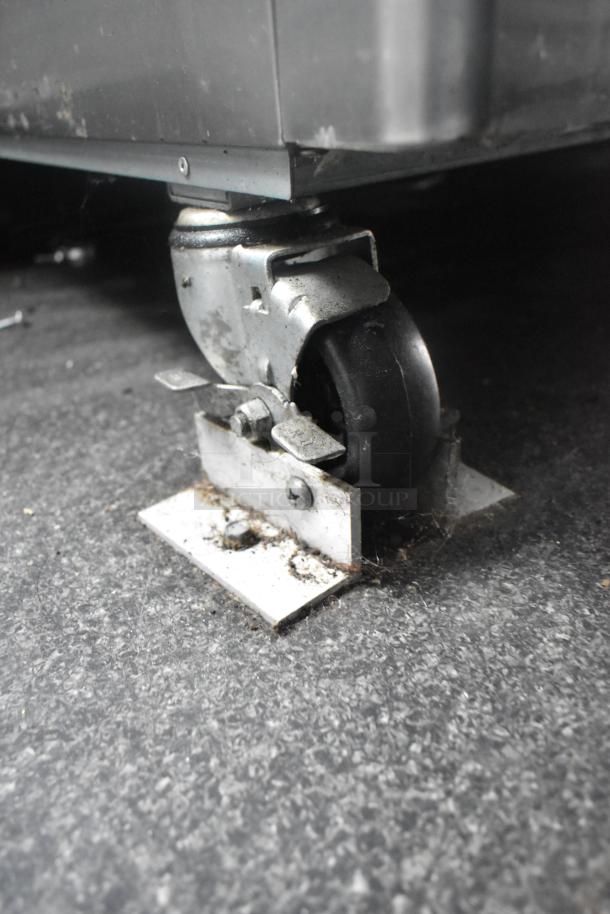 Close-up of a caster wheel on a Southern Dimensions 24' unbranded cold food trailer, showing its metal and rubber structure.