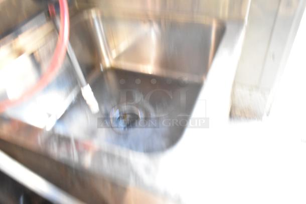 Blurry image of a commercial kitchen sink within a 28' Wendy's fast food trailer. Stainless steel finish.