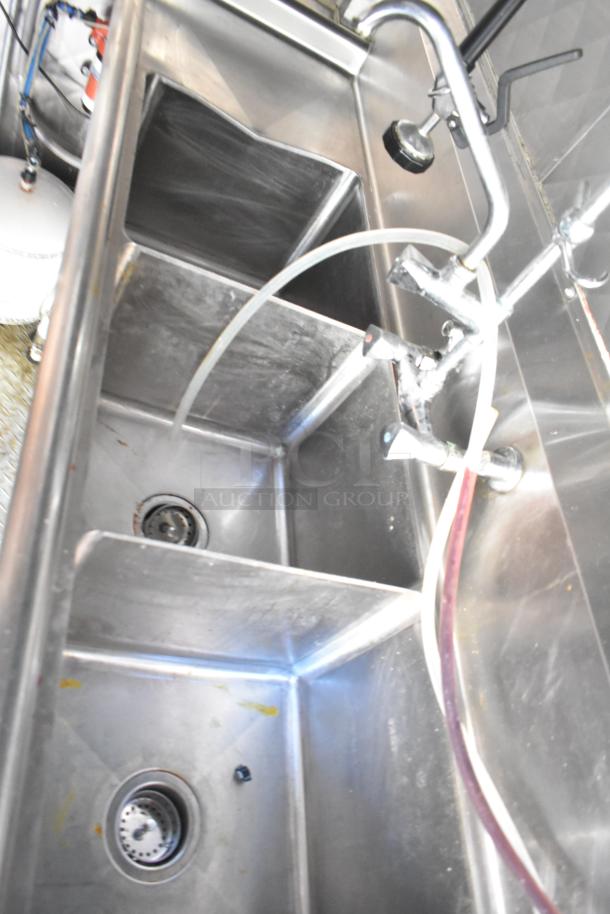 Stainless steel triple sink with faucets in a 28' Wendy's fast food trailer kitchen, showing high-grade commercial equipment.