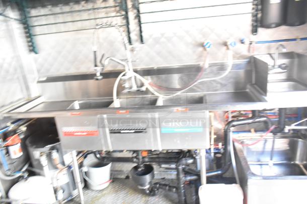 28' Wendy's food trailer interior, featuring commercial-grade stainless steel triple sink, visible plumbing fixtures.