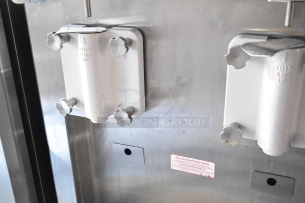 White brackets with "THIS END UP" text on industrial equipment, warning label about moving parts visible.