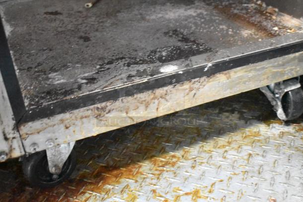 Close-up of a used surface and wheels of a mobile kitchen cart inside a Wendy's fast food trailer. Some wear visible.
