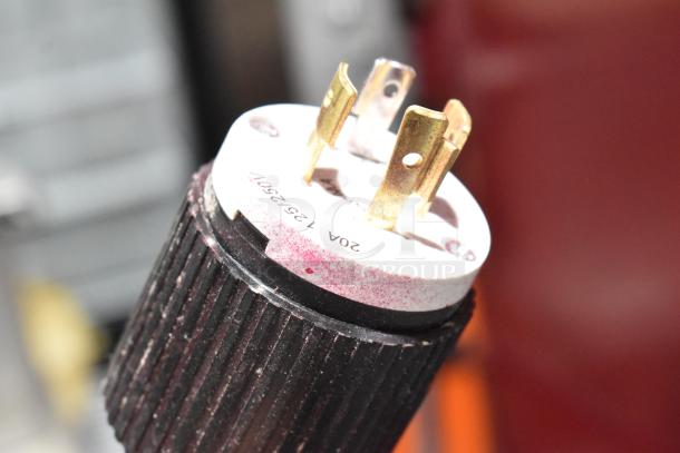 Close-up of a black plug connector, labeled 208 volts, 3 phase, with visible prongs.