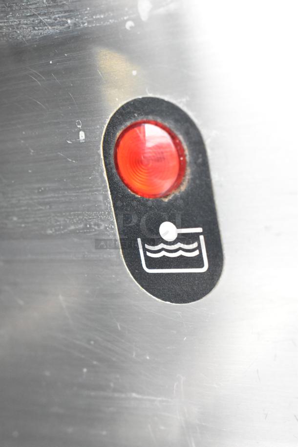 Close-up of a La Cimbali M29 DT/2-NF espresso machine's indicator light. Red light with water level symbol, used for monitoring.