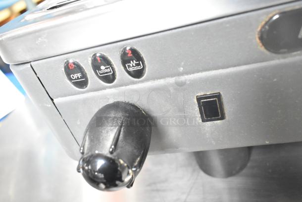 La Cimbali M29 Select DT/2-NF espresso machine control buttons, featuring off and two brewing options. Slight wear visible.