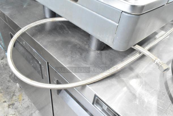 La Cimbali M29 Select DT/2-NF commercial espresso machine, stainless steel hose connected, resting on a countertop.