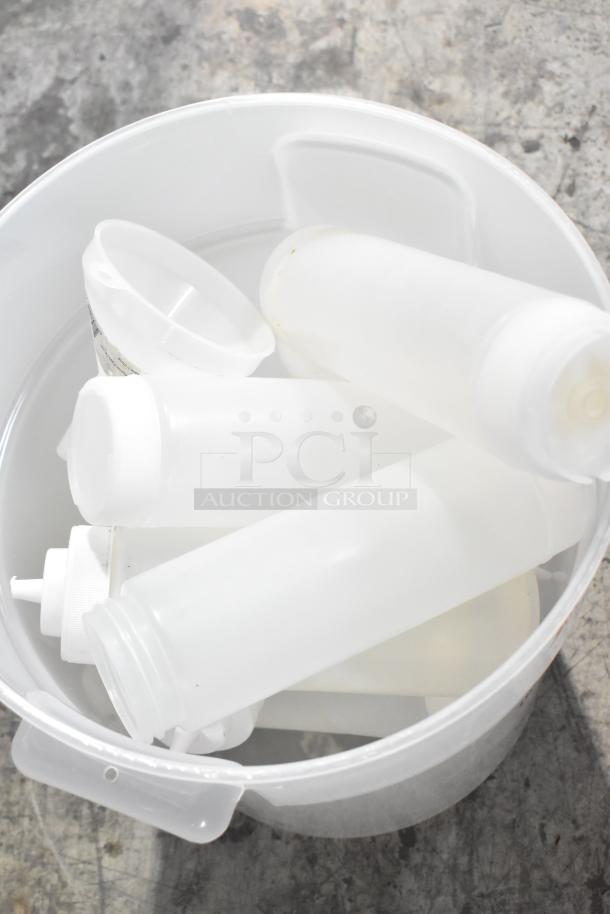 Three-tier lot including white poly bins and lids, cylindrical bottles, and assorted containers in used condition.