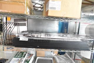 A group of nine various items on a metal shelf, including a cutting board rack and framed pictures, in good condition.