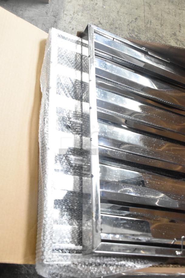 Box of 2 scratch and dent grease hood filters, brand new condition, shiny metal, partially wrapped in bubble wrap.