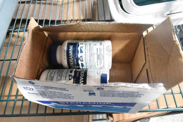 Cardboard box containing Steramine sanitizing tablets, partially open, on metal shelving. Box features product branding.