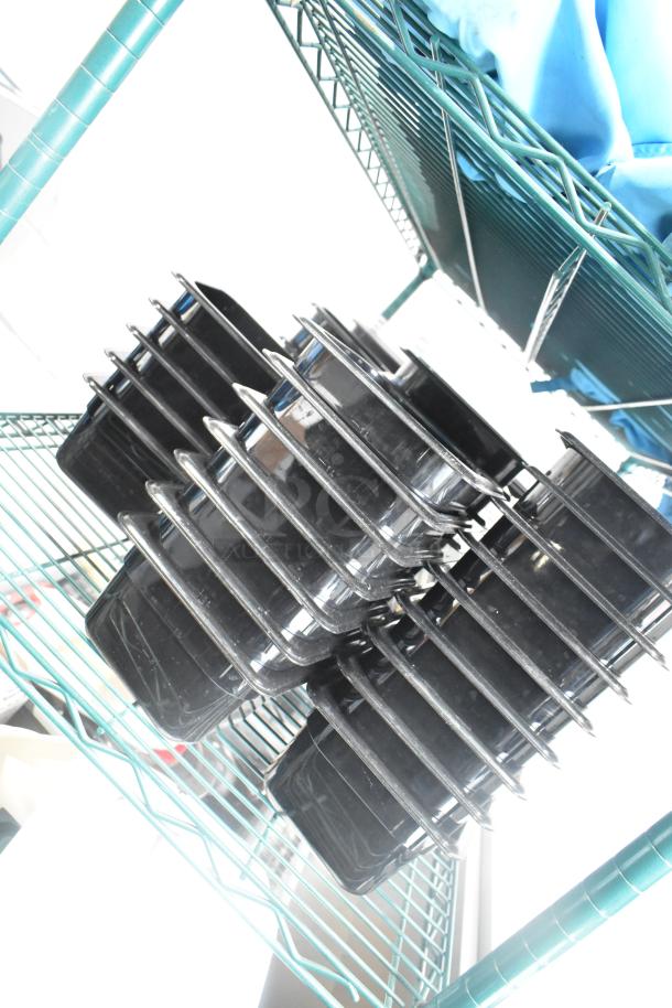 Two-tier lot with poly drop-in bins and utensils on a green wire rack. Black bins stacked; visible condition appears good.