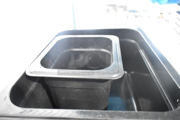 Two-tier lot with poly drop-in bins; black with metallic rims. Includes utensils and ingredient bin, in used condition.