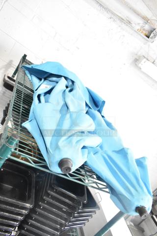 Two blue patio umbrellas, folded, resting on a wire shelf. Fabric appears slightly used. No visible brand markings.