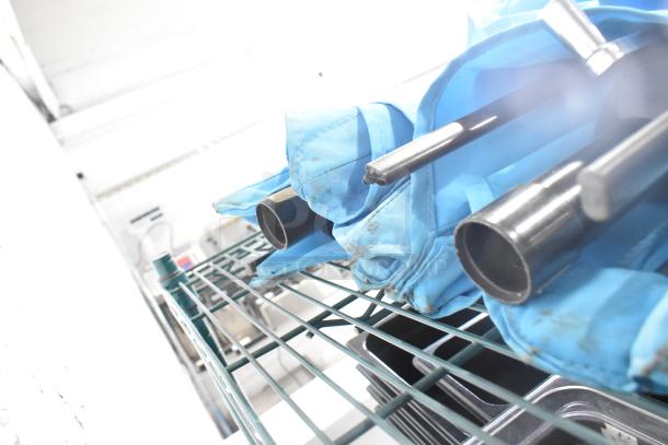 Two blue patio umbrellas, metal poles, mint condition, resting on a wire rack.