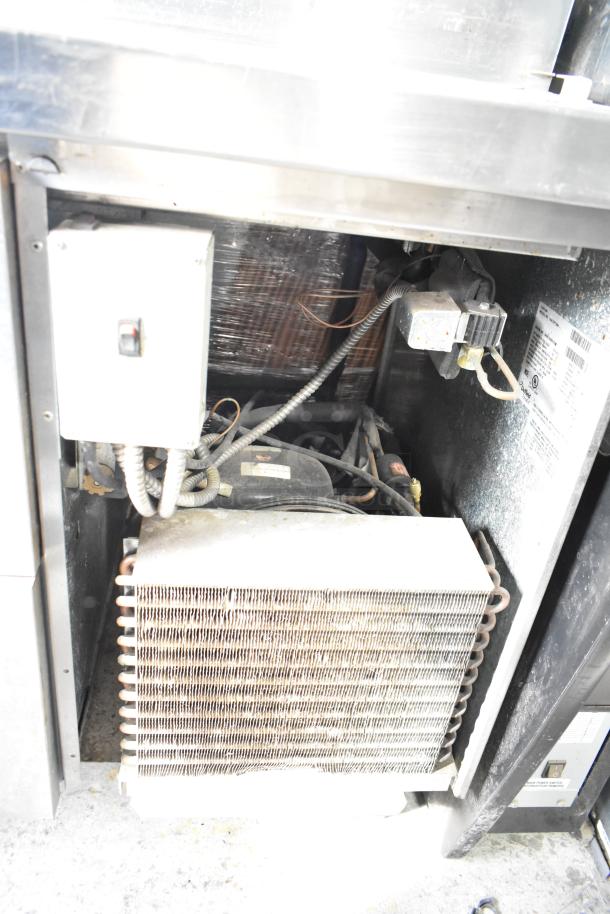 Delfield 18672PTBM-C pizza prep table interior showing refrigeration unit and wiring. Unit powers at 115 volts, 1 phase.