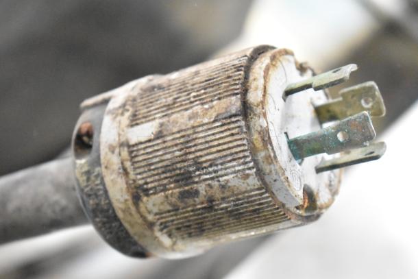Close-up view of a worn electrical plug associated with a commercial floor style pressure fryer. Plug shows rust and corrosion, indicating aged condition.