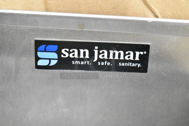 San Jamar lid dispenser with black label reading "smart. safe. sanitary." in a lot including a faucet.