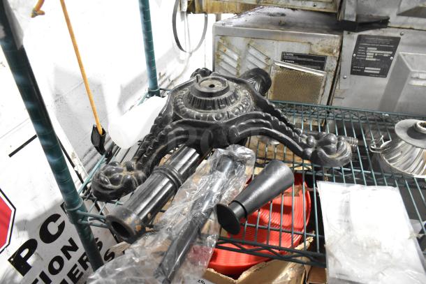 Lot of items on metal shelf; includes black metal base, plastic bottle, black funnel, and miscellaneous kitchenware.