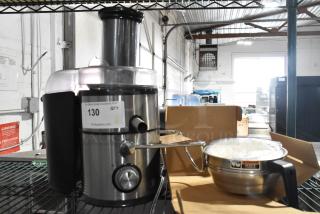 Stainless steel countertop juicer in good condition, with a control dial, spout, and clear lid. Auction label 130 attached.