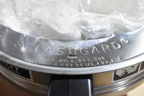 Metallic countertop juicer close-up showing "SPLASHGARD" label with patent numbers engraved on the surface.