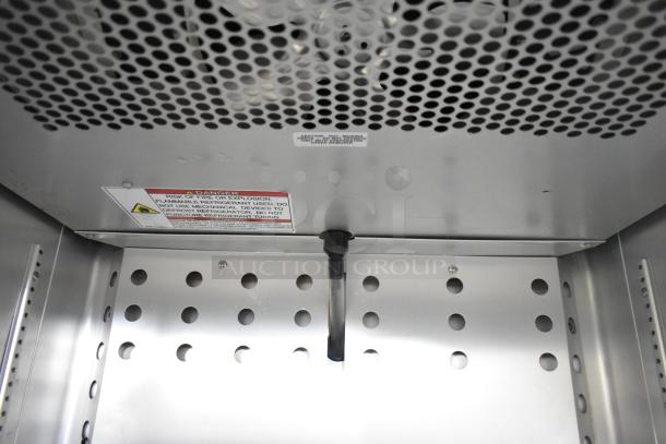 Interior view of 2021 True T-19F-HC freezer, showing perforated metal shelf and safety warning label inside.