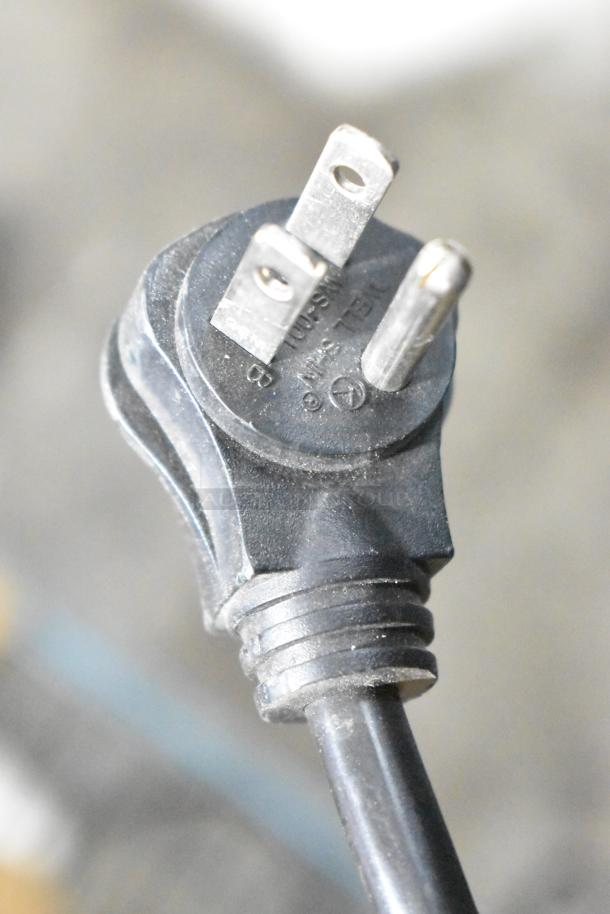 "Close-up of a black power plug from an APC Uninterruptible Power Supply, showing dust and slight wear."