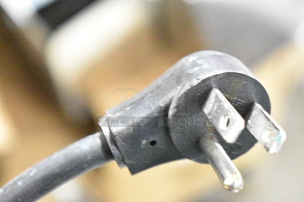 Close-up of a power cord plug for an APC Uninterruptible Power Supply, showing metal prongs and black casing.