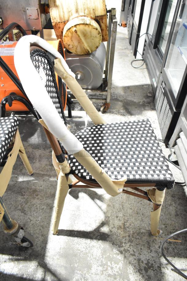 Black and white checkered weave rattan outdoor side chair with protective wrapping. Lancaster Table & Seating. New, scratch and dent.