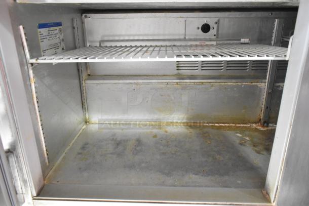 Beverage Air commercial sandwich prep table interior, showing metal shelving and slight wear. Model details on label inside.