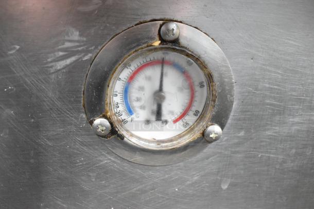 Close-up of a thermometer on a commercial 2 drawer chef base. Metal surface shows signs of wear. Temperature gauge is visible.