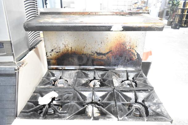 Vulcan commercial gas-powered 6 burner range with oven, over shelf, and backsplash. Shows signs of wear and use.