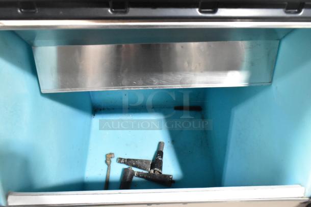 Manitowoc commercial ice machine head on bin, stainless steel interior, used condition, visible components inside.