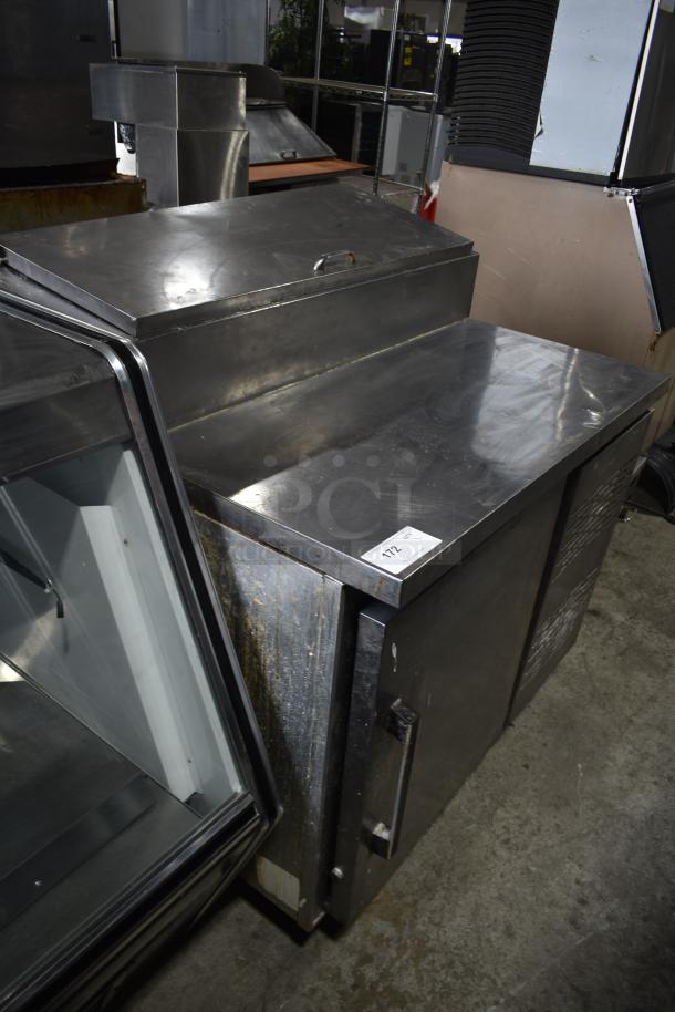 Migali commercial pizza prep table in stainless steel. Features include a single door, 115 volts, 1 phase. Visible wear.